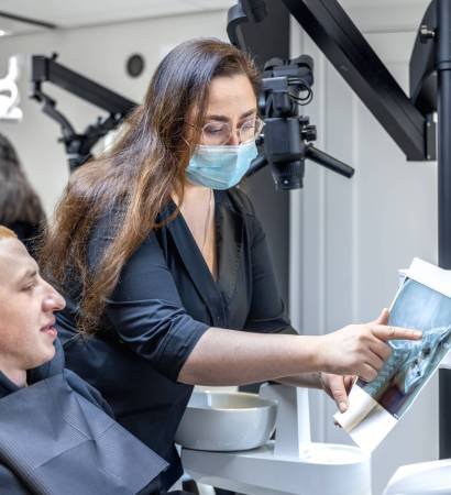 Young female dentist showing a patient a dental x-ray. Dentistry concept. High quality photo. Dentist at work. Dentist and patient. Mask on a woman's face.